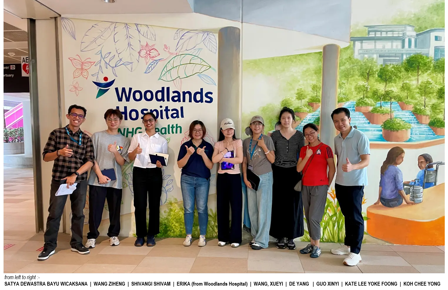 Group 5 team members with Woodlands Hospital staff in front of the hospital mural